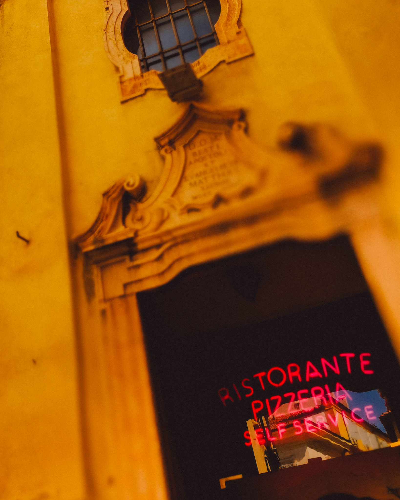 A bright yellow wall with a pizza restaurant sign in bright pink neon, Verona, Italy, September 2017, Huawei Mate 9 Pro.