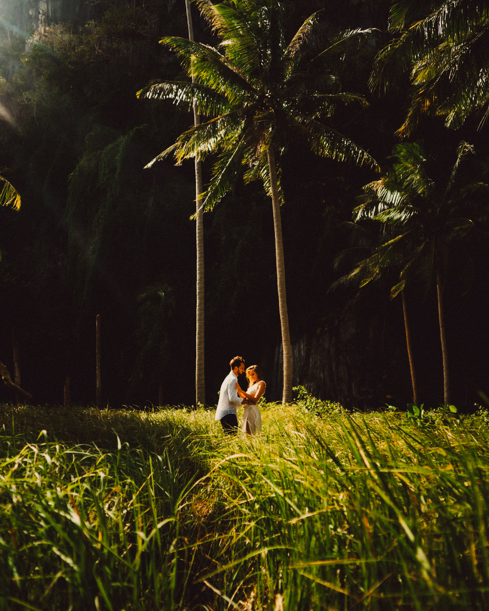 Moody couple portraits with a tropical vibe against a shadowy limestone cliff, palm trees and knee-high cogon grass, Pinagbuyutan Island, El Nido, Palawan, Philippines, Southeast Asia, December 2019, Sony A7III.