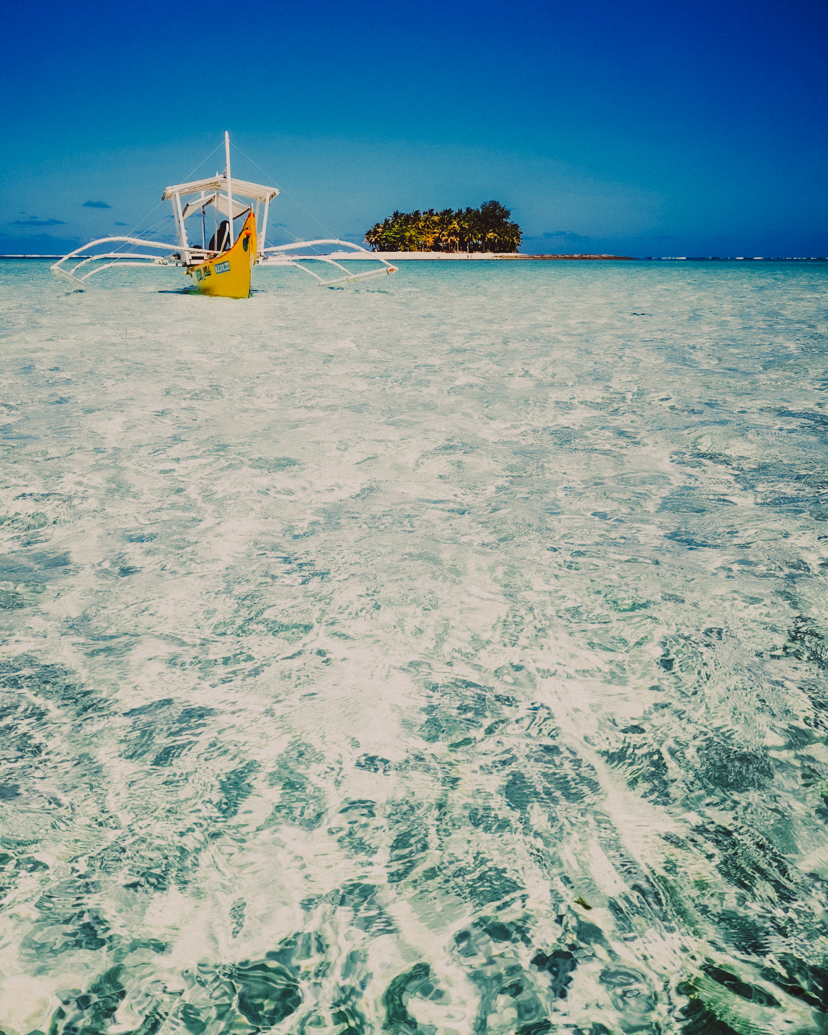 A yellow outrigger boat floating above Secret Sandbar at lowtide, with Guyam Island in the background, Siargao Island, Philippines, March 2019, Huawei Mate 20 Pro.