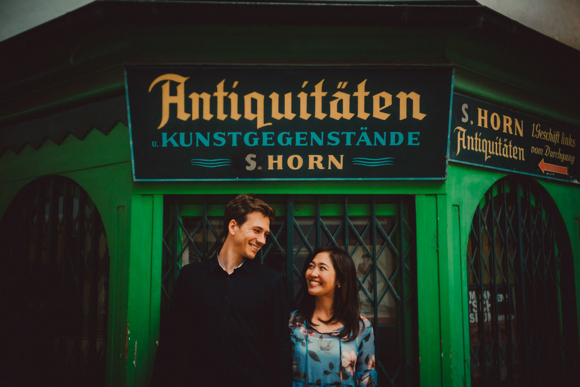 The couple standing side by side in front of a quaint Viennese shop, Innere Stadt, Vienna, Austria, August 2017, Sony A7RII.