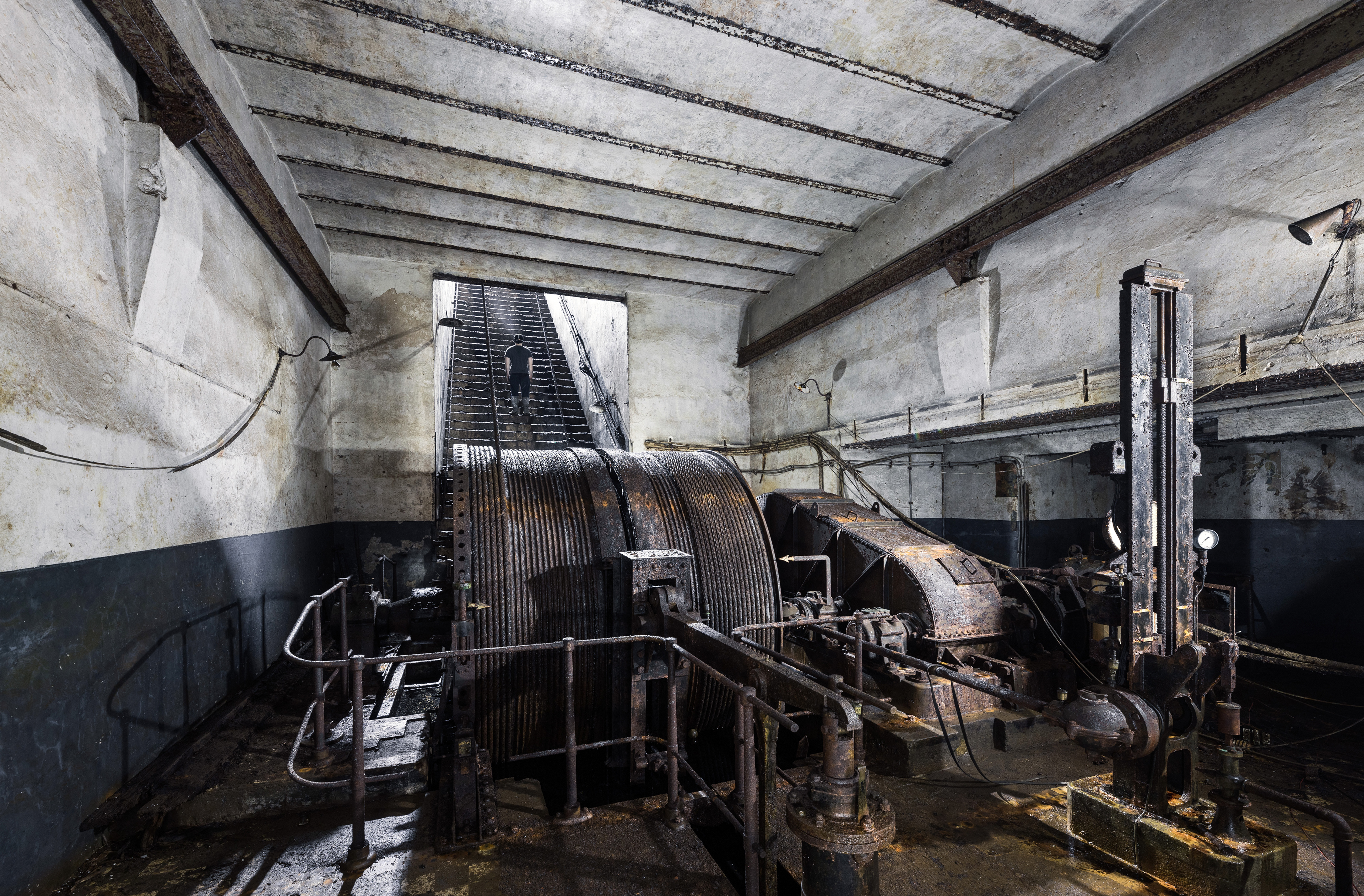 Salle souterraine contenant un énorme double treuil. Il permet de faire descendre et monter des cages vers les niveaux les plus profonds de la mine.