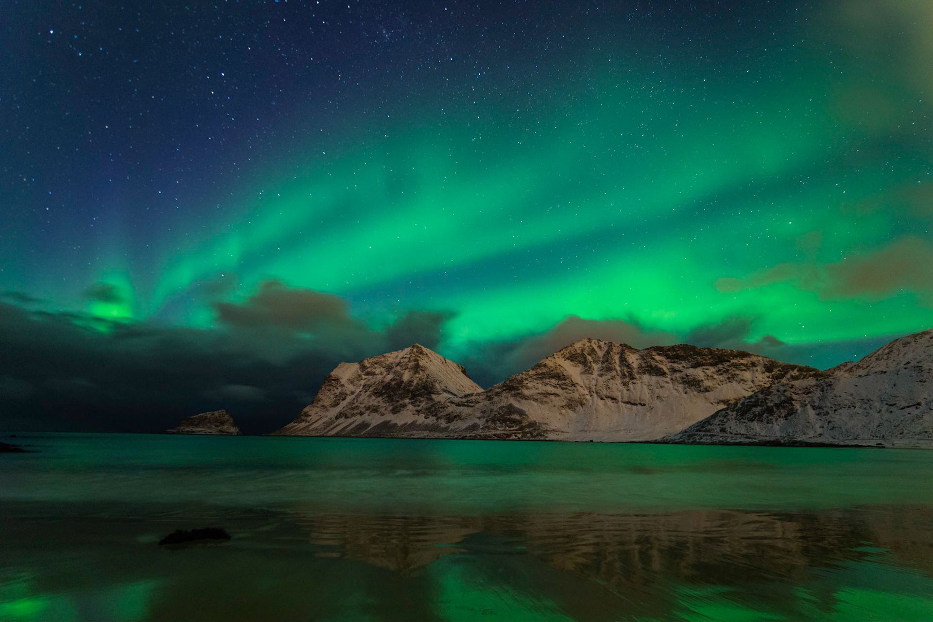 The northern lights dancing behind periodic clouds bringing snow squalls at Haukland Beach.Leknes, Nordland, NorwayMarch 19, 2018PENTAX K-1, HD PENTAX-D FA 15-30mm F2.8ED SDM WRISO 3200 16 mm  10.0 sec at ƒ / 2.8