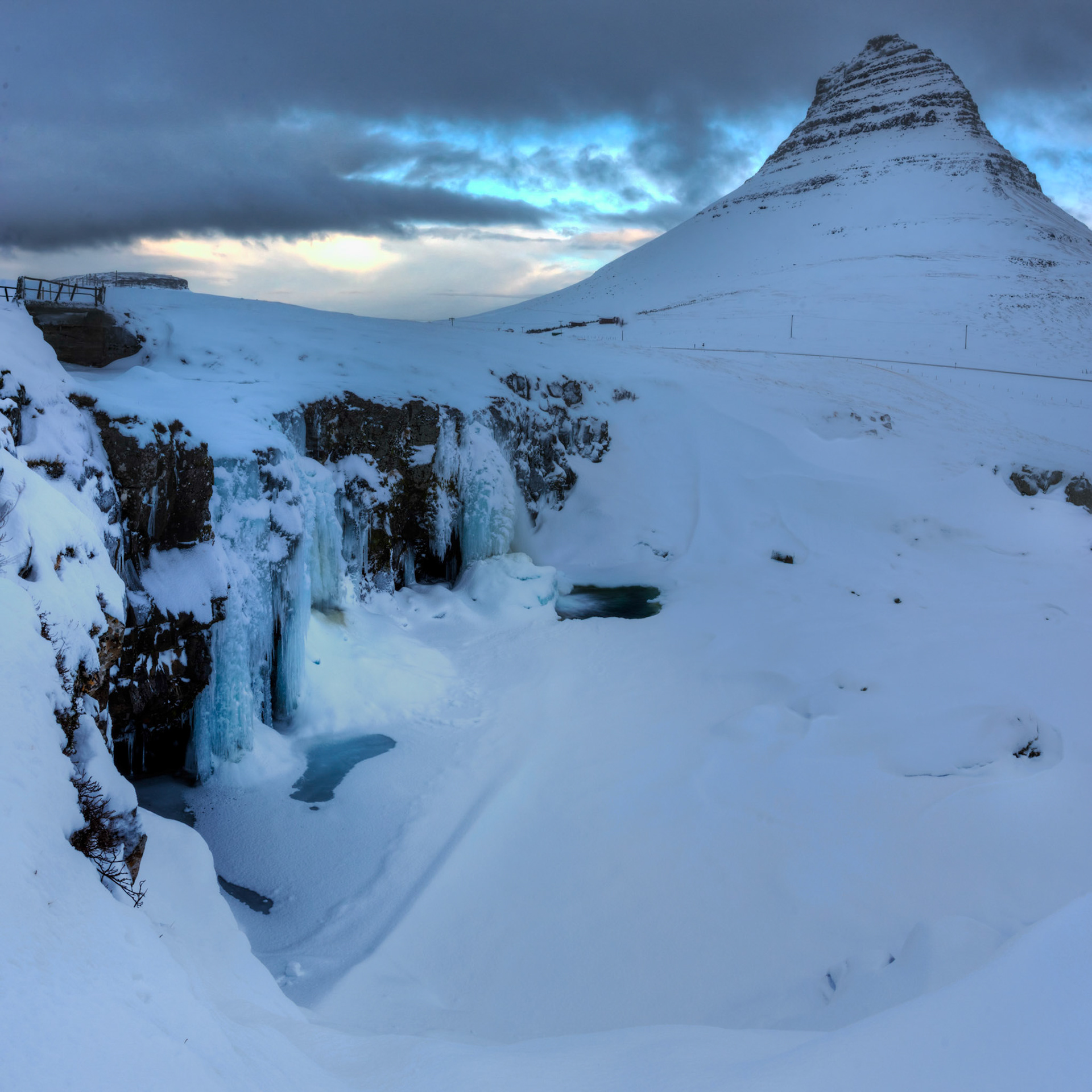 The iconic mountain of Kirkjufell, and Kirkjufellsfoss.Vesturland, IcelandFebruary 6, 2016This is an HDR panoramic image consisting of 3 frames comprised of 5 exposures each. HDR processing performed in Photomatix Pro.  Panoramic stitching performed in Photoshop. Additional processing performed in Lightroom and Photoshop.PENTAX K-3, Sigma 18-35mm f/1.8 DC HSM ArtISO 100 18 mm  0.4 sec at ƒ / 16