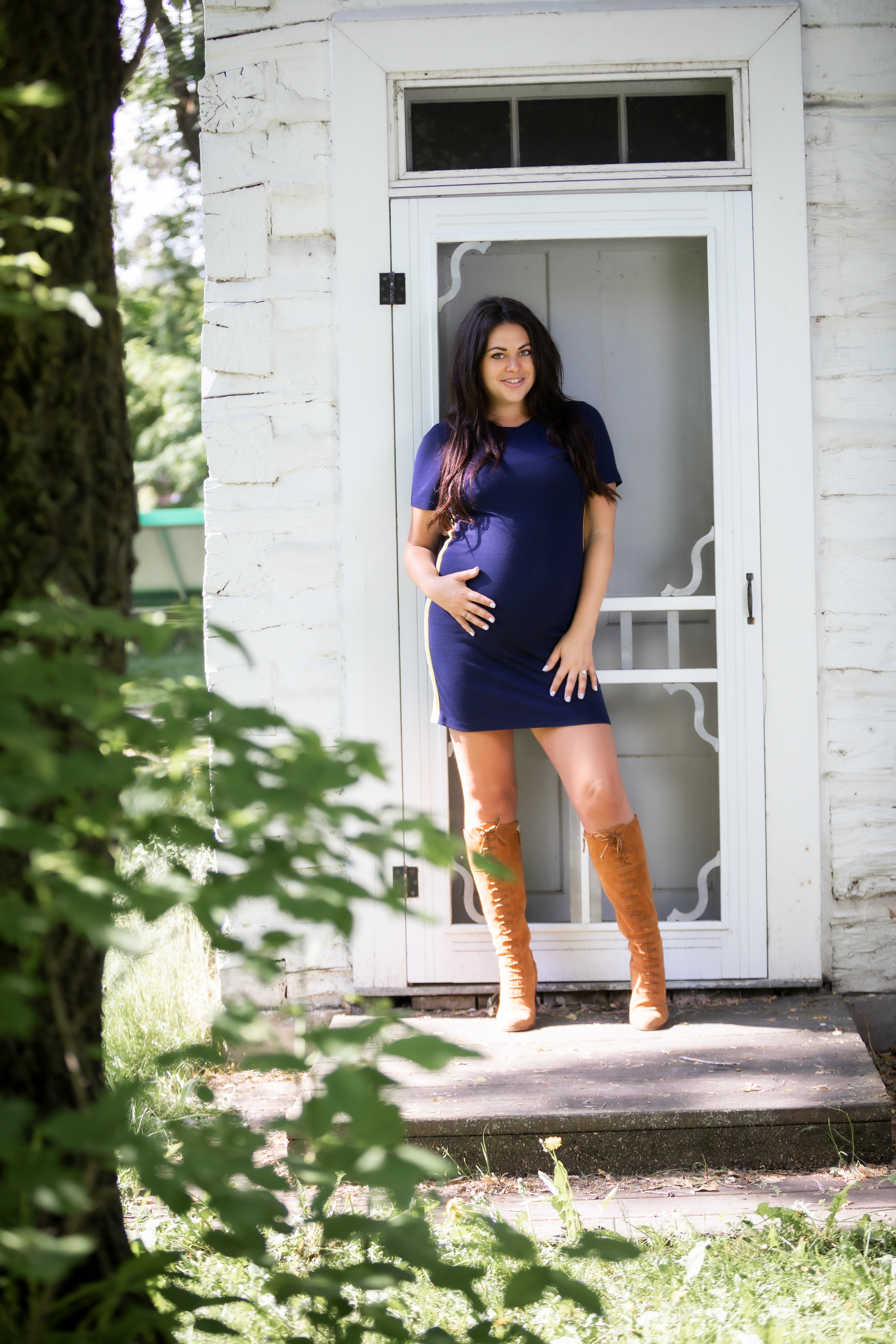 mom holding belly smiling standing at front door