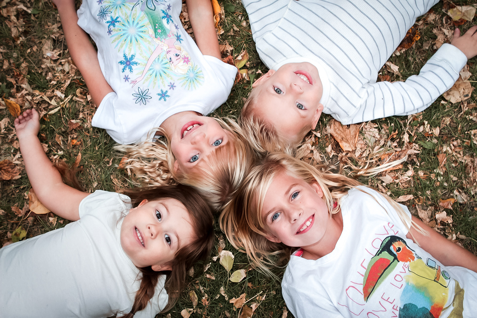 4 kids laying in fall leves