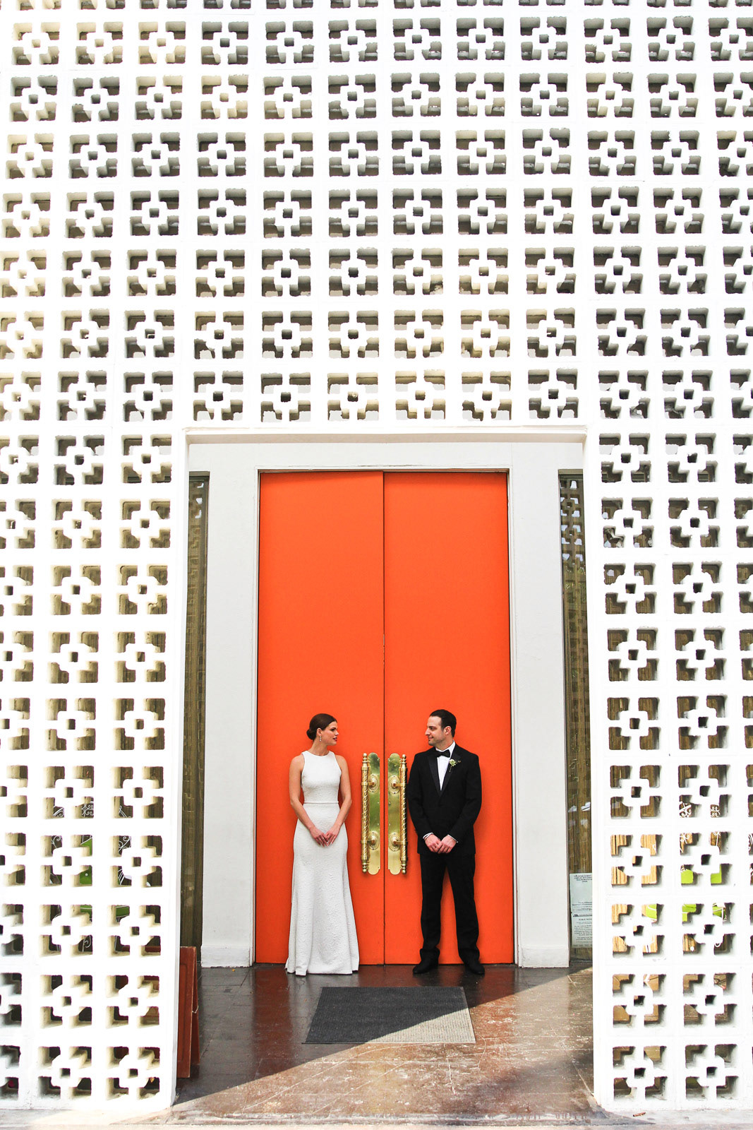 Unique perspective of wedding couple in front of bright orange doors