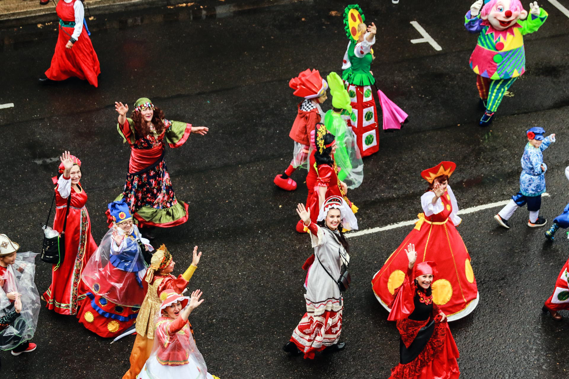 Group of women in costume walking in Eugene parade, looking up and waving to the camera