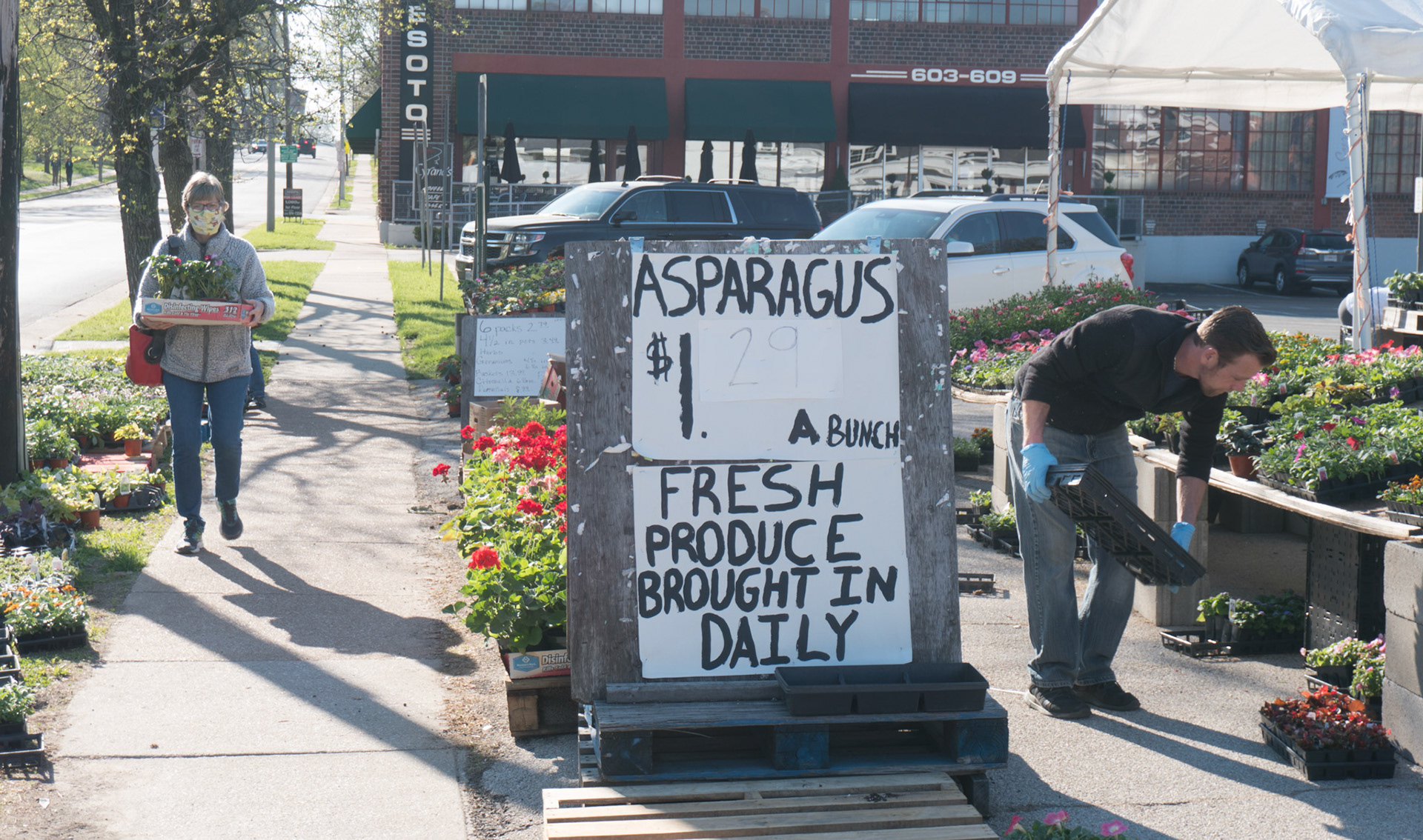 Manager Joe Whitnell, right, works in the outdoor section of Roger’s Produce in Webster Groves, 625 E. Lockwood Ave, on April 10, 2020, while customers wearing face masks and other protective gear shopped around the section for flowers and other produce items. Whitnell said the pandemic has improved the amount of business the grocery store gets, as he thinks more people are at home cooking.