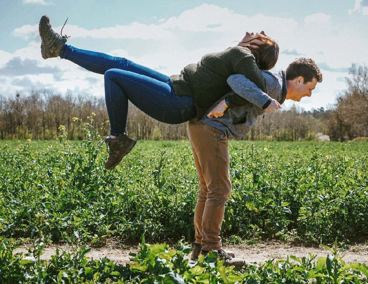 man pulling his girlfriend up into the air by his arms at pre wedding engagement shoot with bucks photographer david lefebvre near endeavour woodland venue in buckinghamshire near winslow