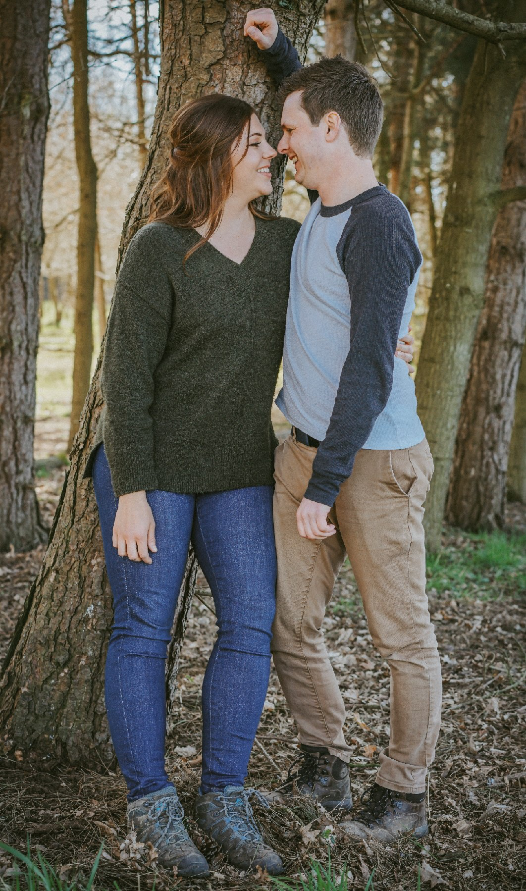 newly engaged pair stood happily smiling at each other leant against a tree at outdoor wedding venue endeavour based in swanbourne buckinghamshire they are on a candid pre wedding session with david lefebvre