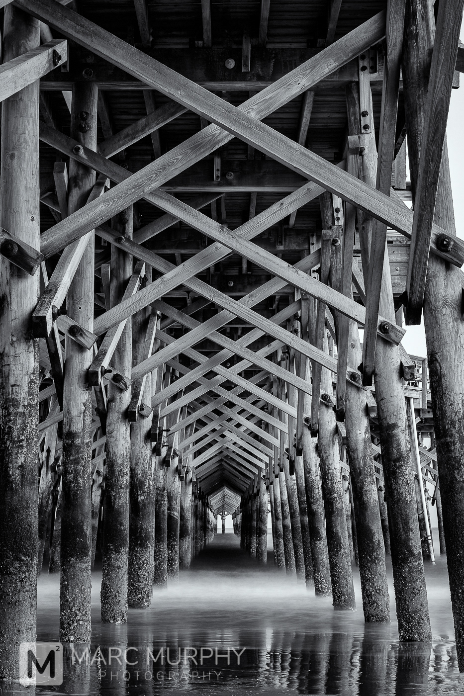 Black and White Underside of Pier on Beach Coastline