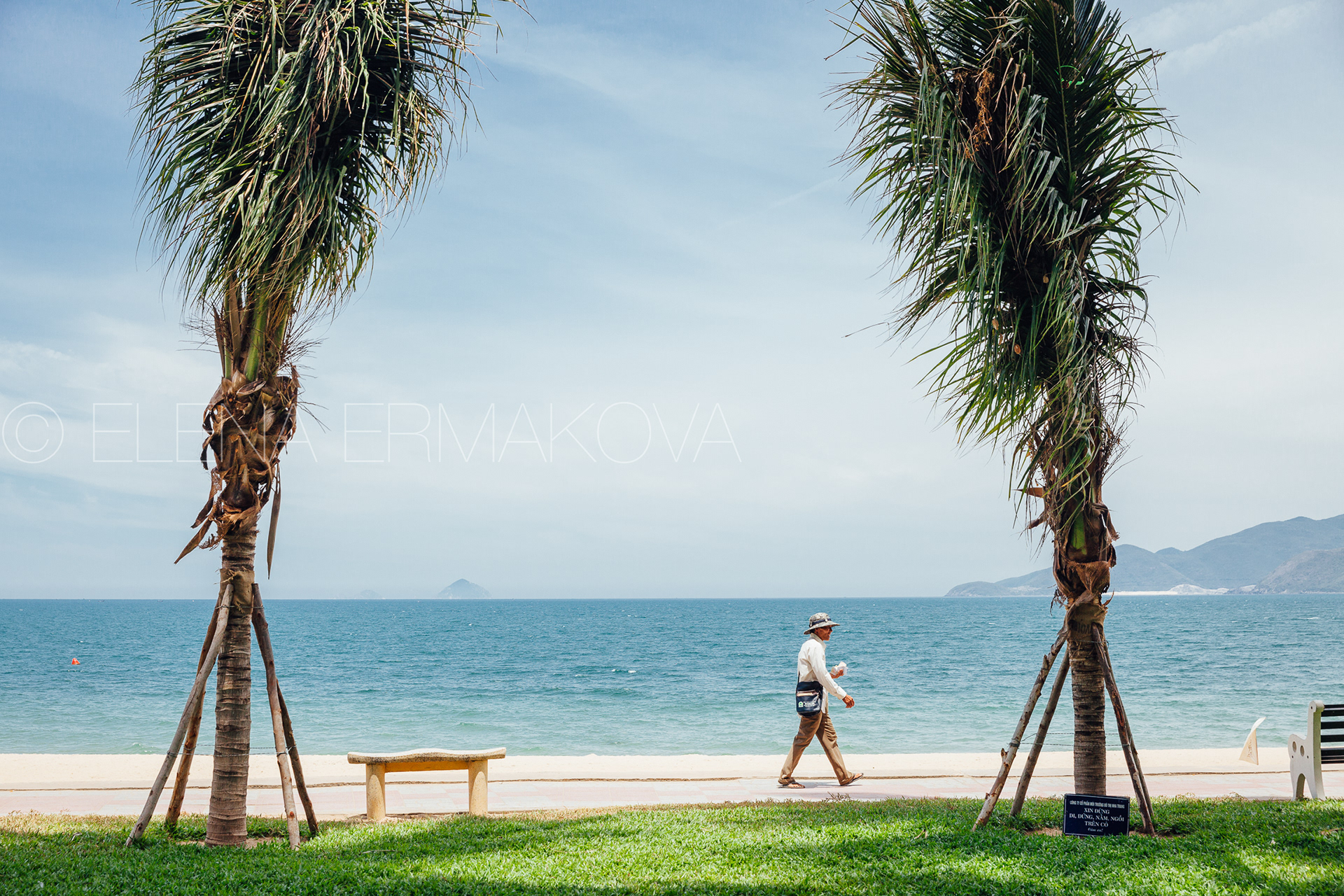 Hard workers on the beach by Elena Ermakova: Beach vendor carries goods for sale along the promenade, September 02, 2018, Nha Trang, Vietnam