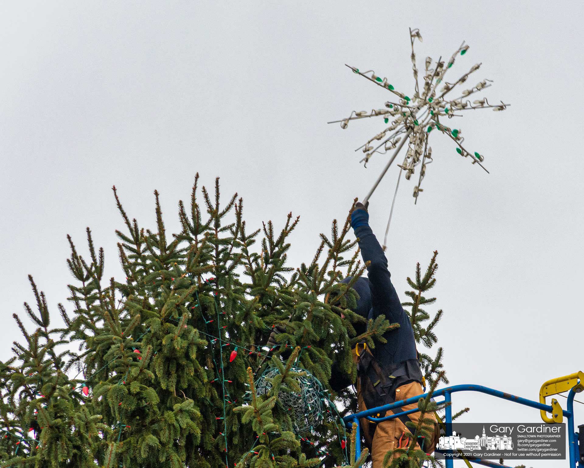 A city park worker removes the star from atop the Christmas tree on the civic green at city hall marking the end of the holiday season for a portion of Uptown. My Final Photo for Jan. 4, 2021.