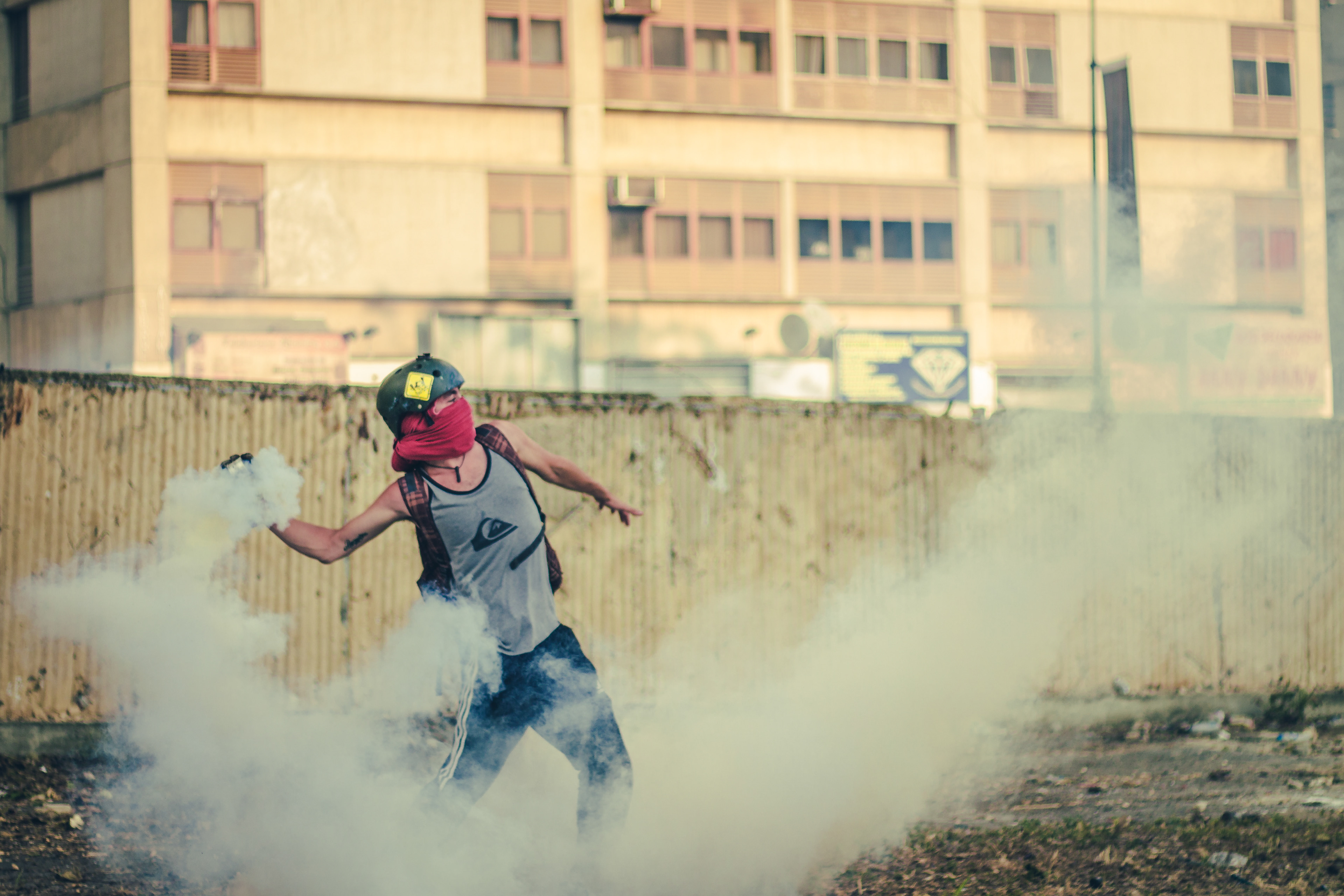 A protester throws back a tear gas canister at the police, Caracas 2014