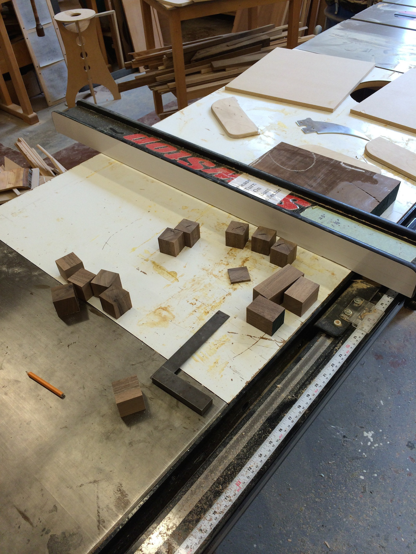 The dice were made in the woodshop from a larger piece of walnut. It was cut down into a 1.5" x 1.5" strip and then into individual cubes on the tablesaw.