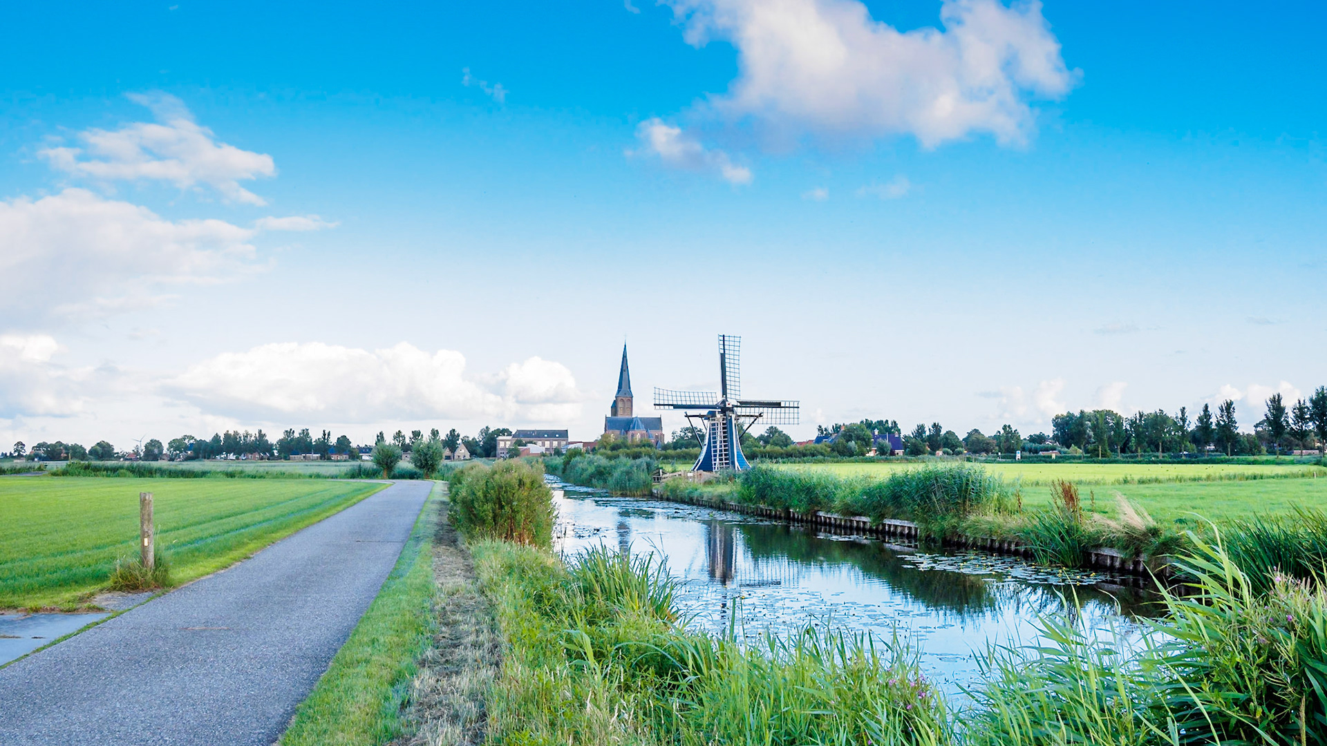Windmill reflected in the water under a blue sky