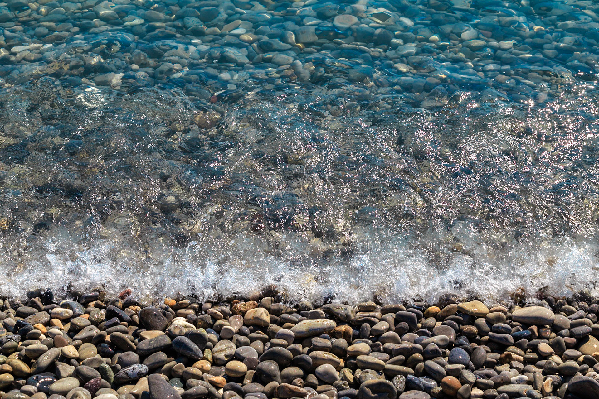 Tides wash a pebble beach during the day.